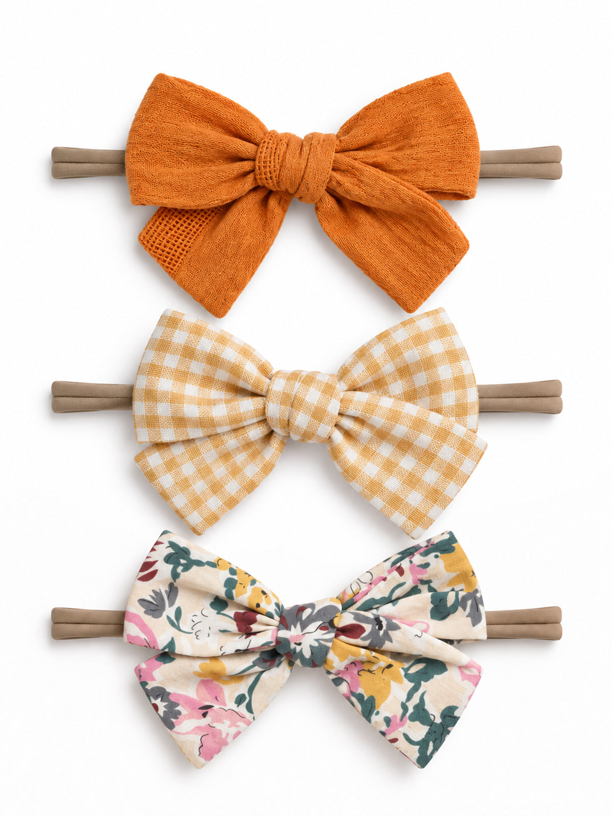 Three hair bows: orange textured, yellow gingham, and floral print, all on elastic bands. Suitable for kids' accessories.