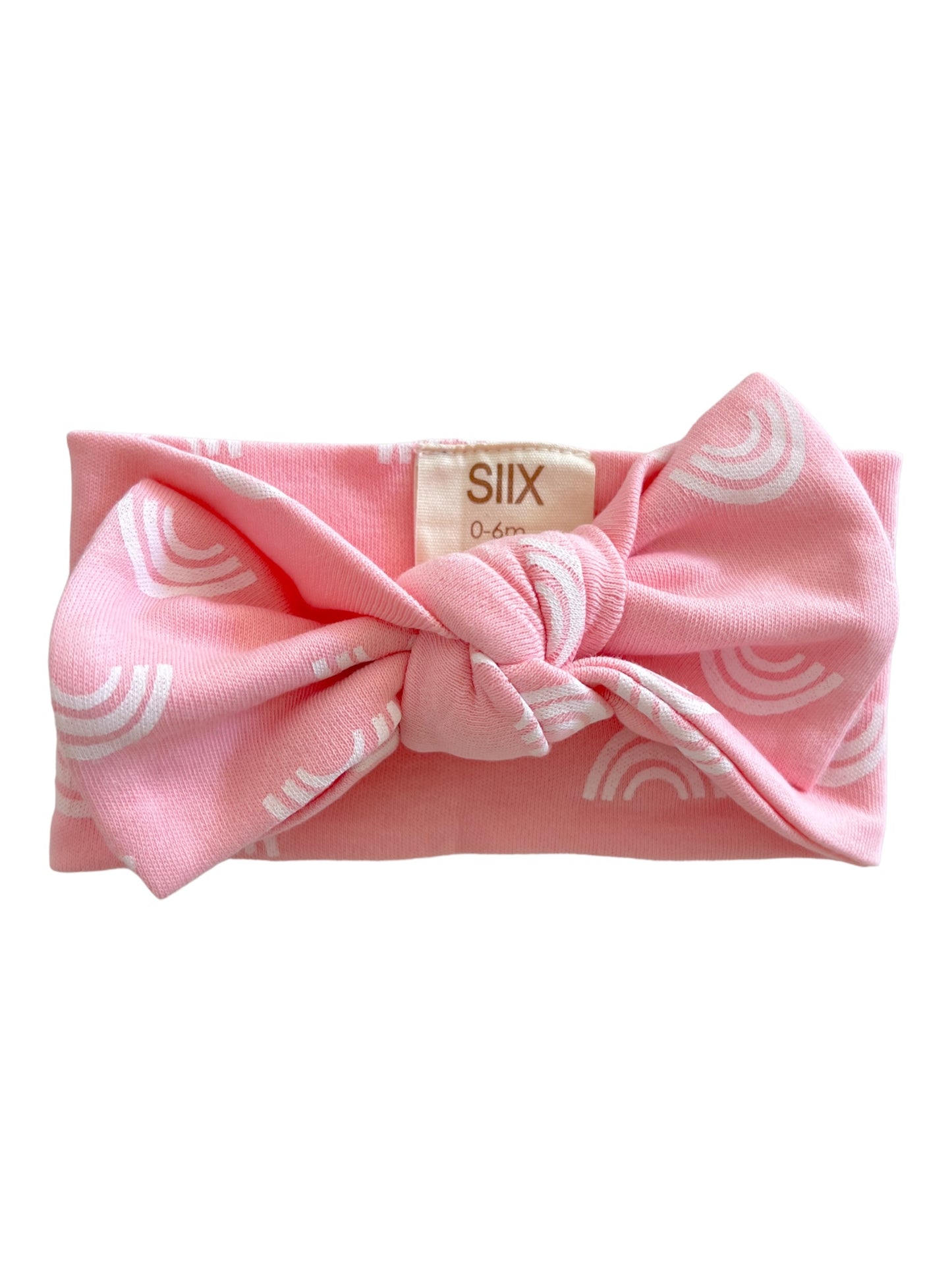 Pink baby headband with a knot and white rainbow patterns, labeled size 0-6 months.