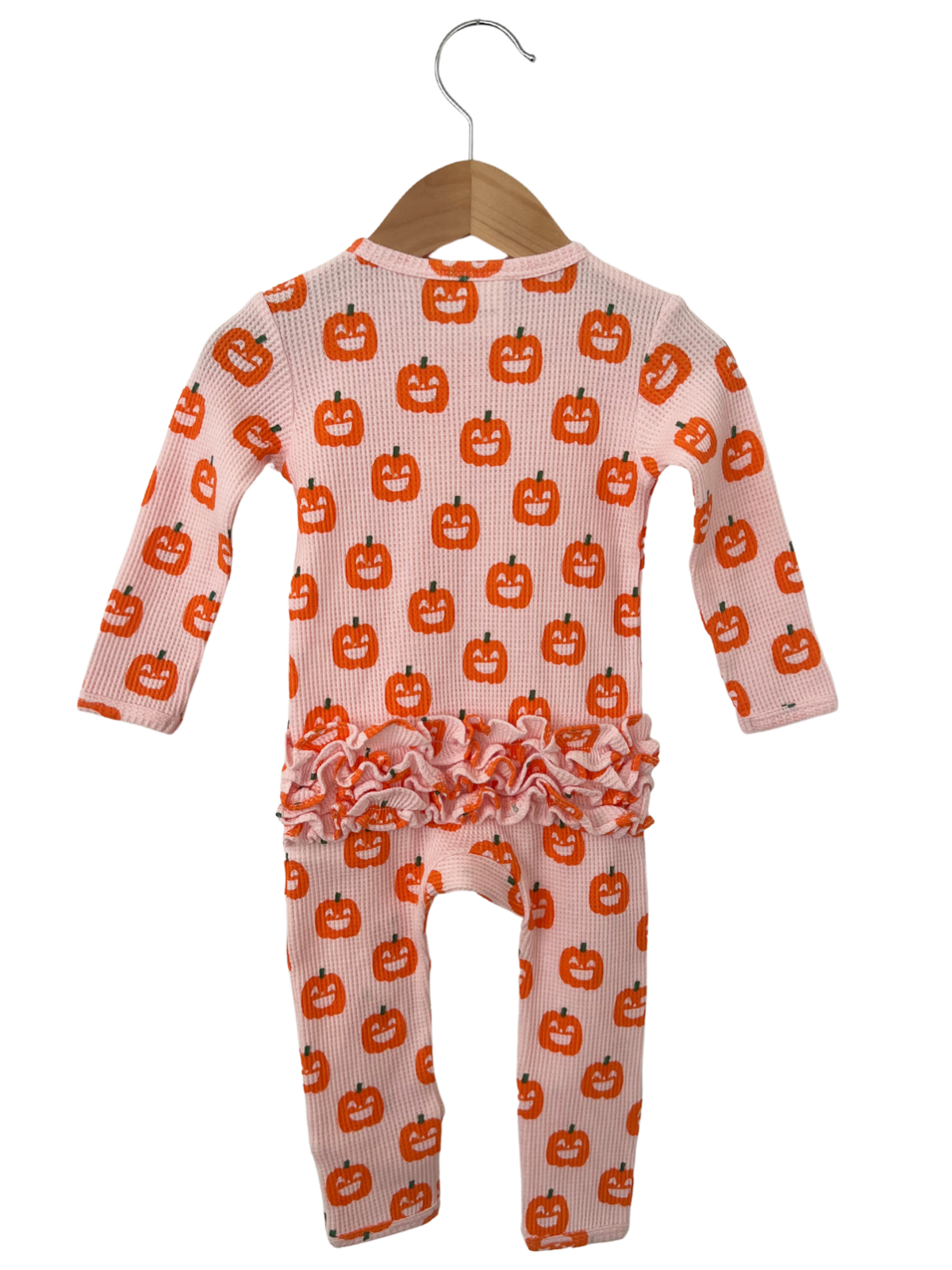 Pink baby outfit with pumpkin print and ruffled hem, hanging on a wooden hanger. Perfect for fall celebrations.