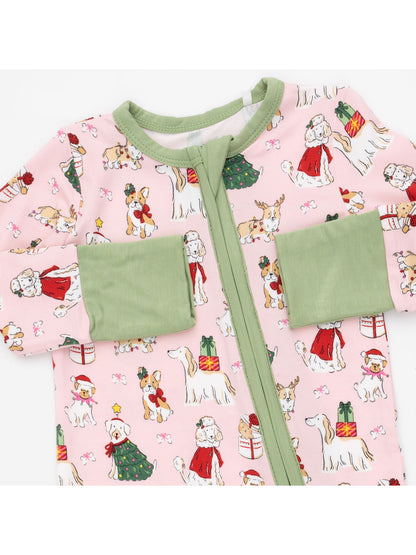 Pink pajama onesie featuring festive dogs, Christmas gifts, and holiday decorations with green cuffs.