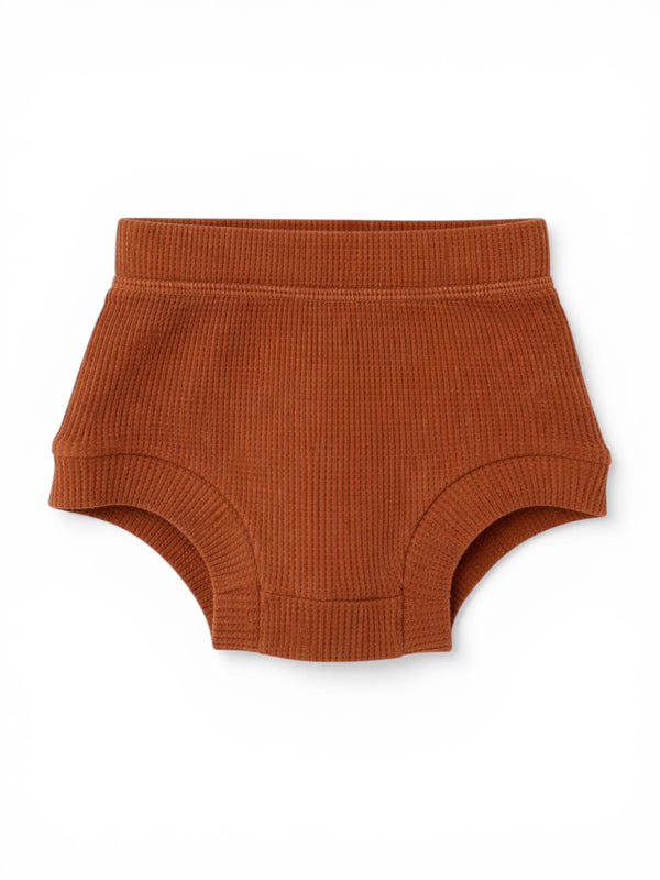 Rust-colored ribbed toddler underwear on a white background.
