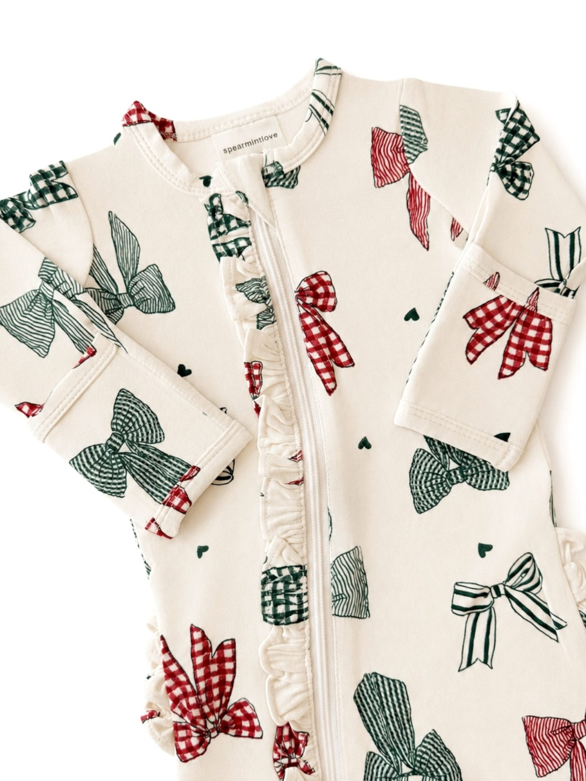 Infant bodysuit featuring colorful bows on a cream background with ruffles and a front zipper.