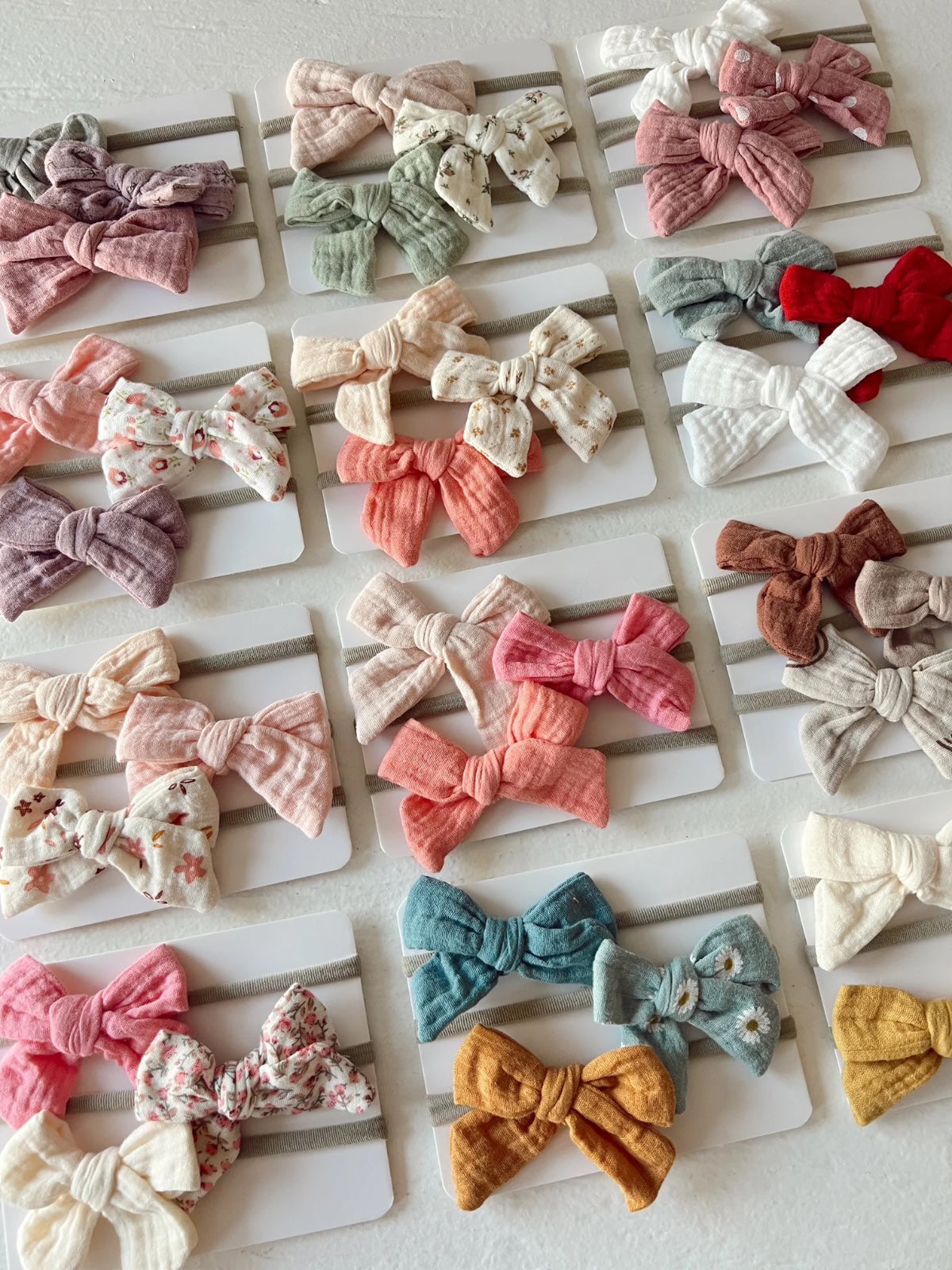 Assortment of colorful fabric hair bows displayed on cards, featuring various patterns and textures.