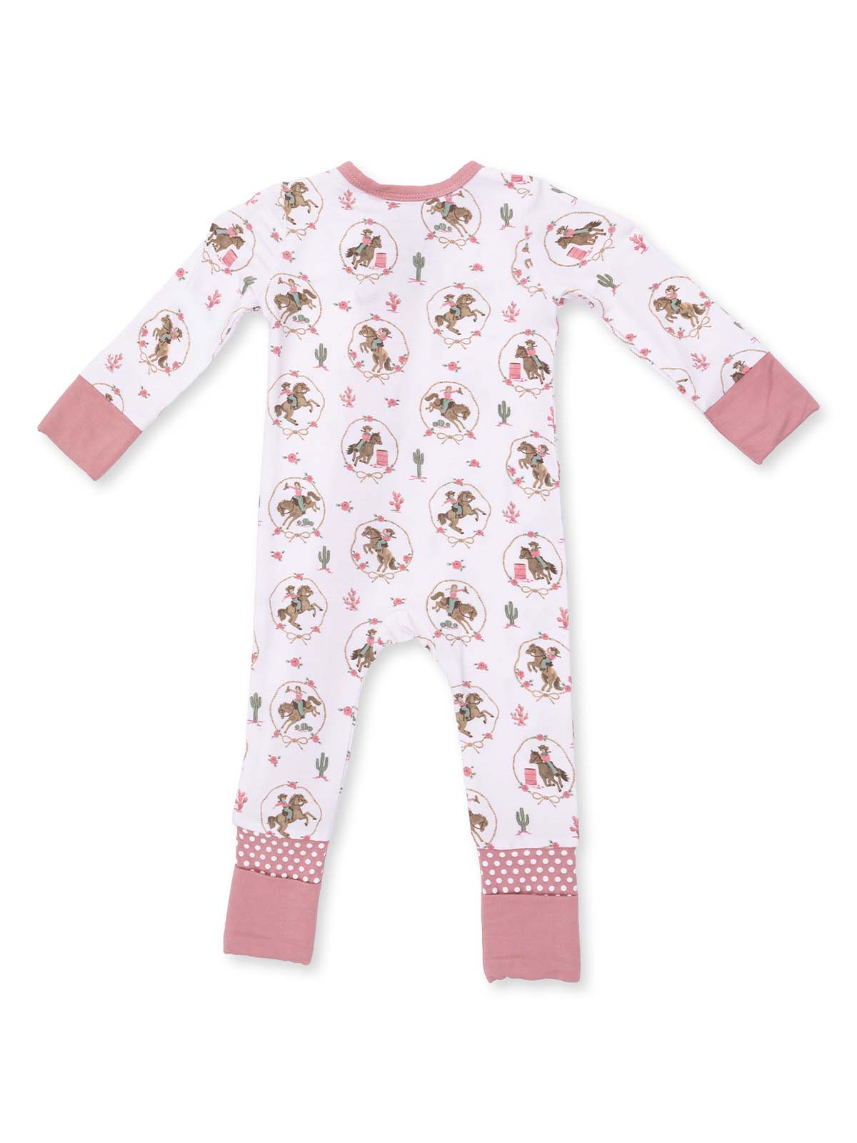 White infants’ jumper with playful print of cartoon cowboys and cacti, featuring pink accents and polka-dot cuffs.