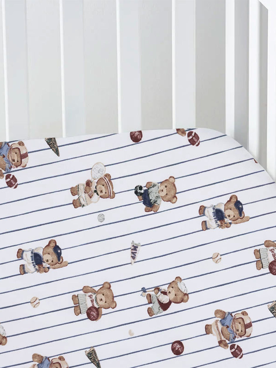 Crib sheet featuring playful teddy bears in sports attire on a blue striped background.