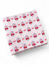 Pink fabric with a cherry pattern, featuring small red cherries and bows on a checked background.