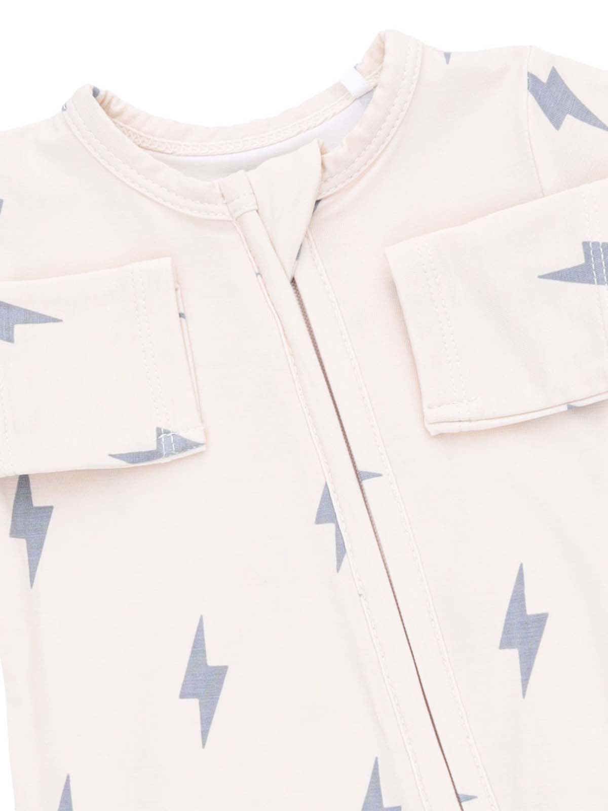 Light-colored baby outfit with gray lightning bolt patterns and a zip front. Designed for comfort and style.
