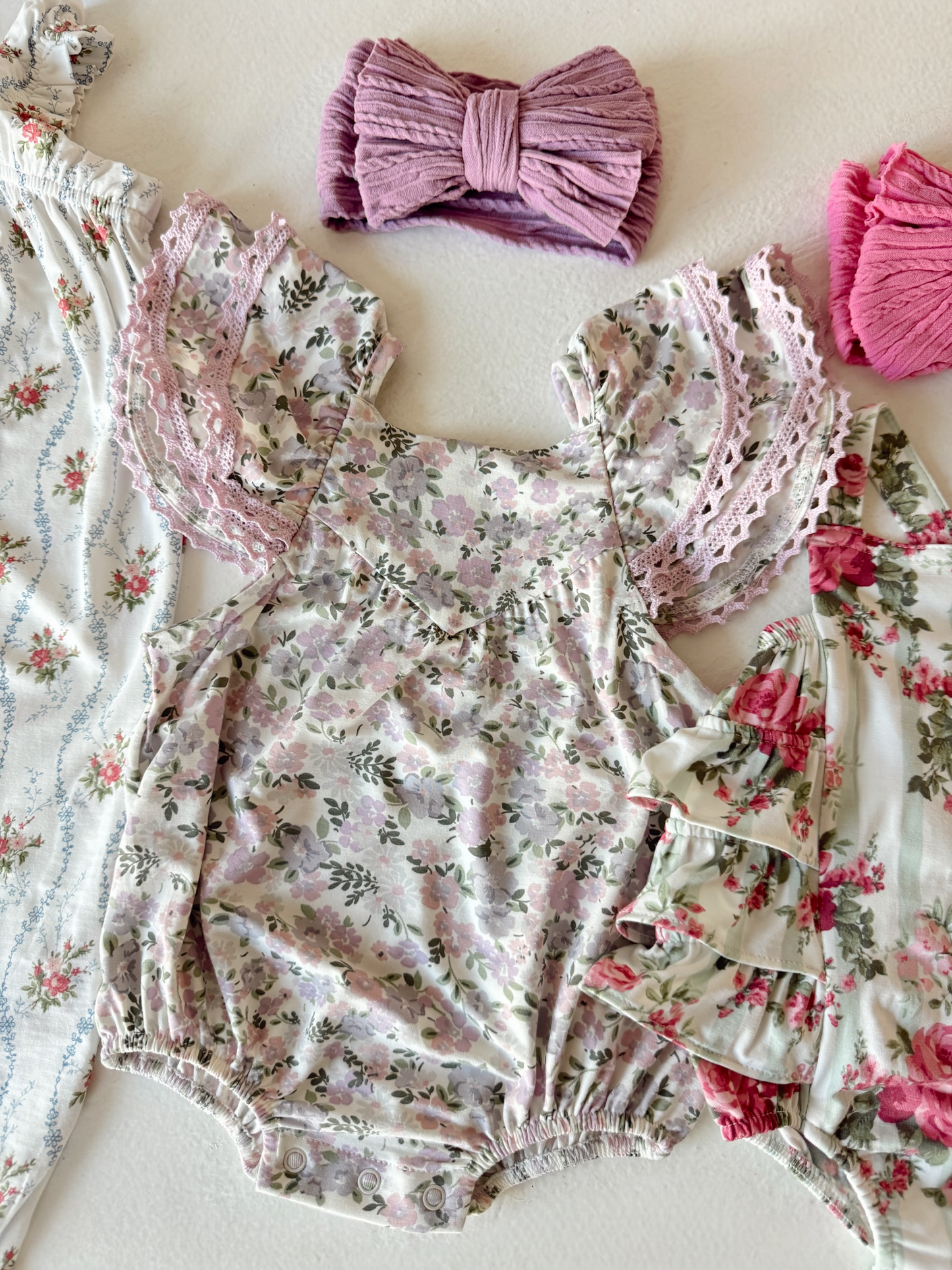 Baby girl outfits featuring floral patterns and coordinating hair accessories in soft pastel colors.