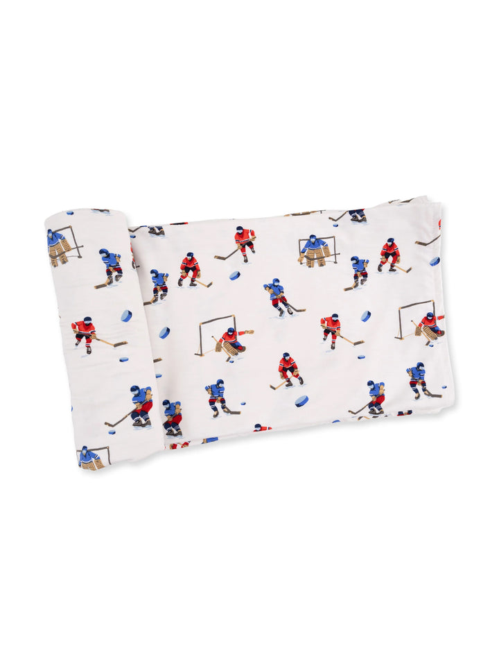 Hockey-themed fabric featuring colorful illustrations of players and goalies in action on a light background.