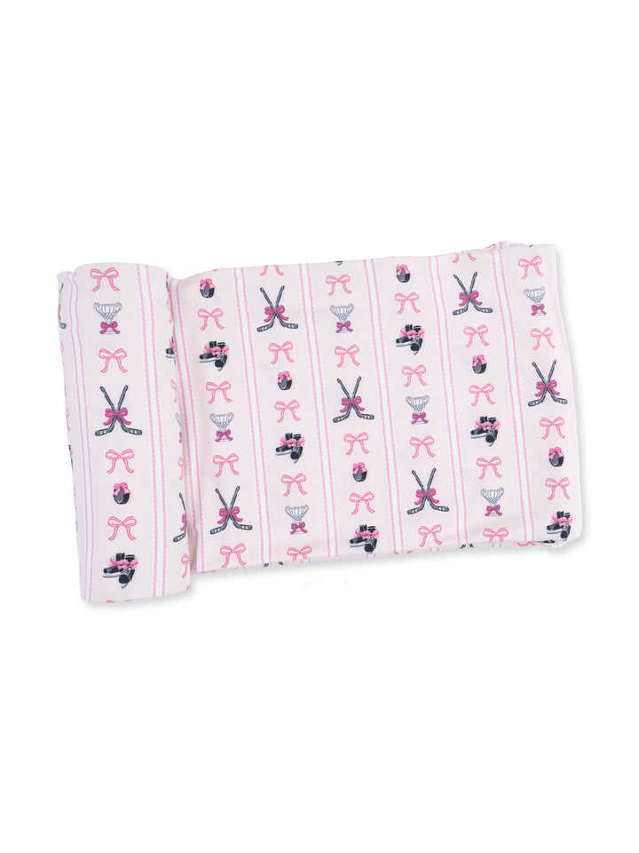 Child's blanket featuring a pink pattern with bows, ballet shoes, and hockey skates.