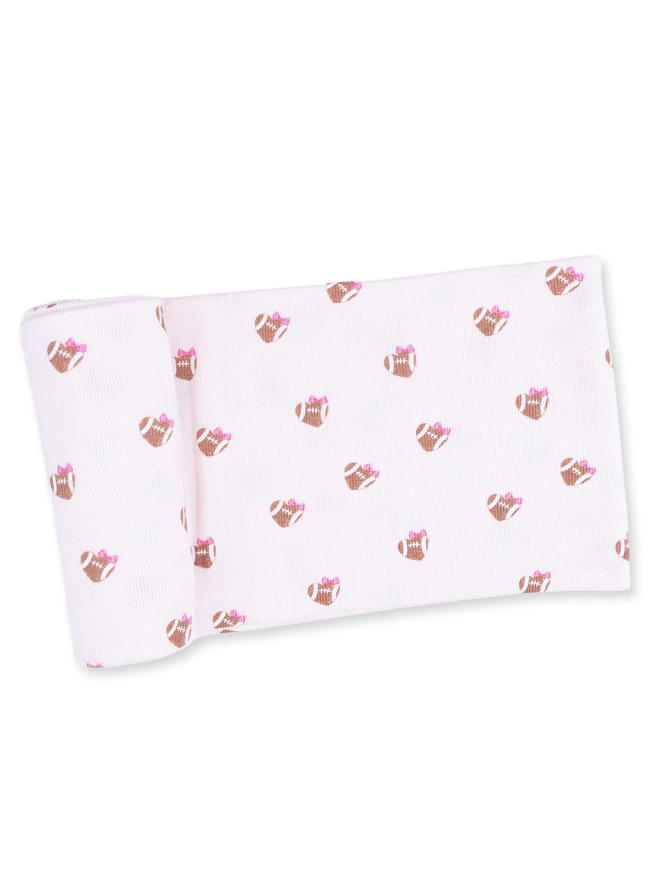 Light pink fabric featuring a repeated pattern of brown footballs adorned with pink bows.
