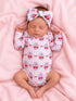 Baby girl sleeping on a pink blanket, wearing a cherry-patterned onesie and a matching headband.