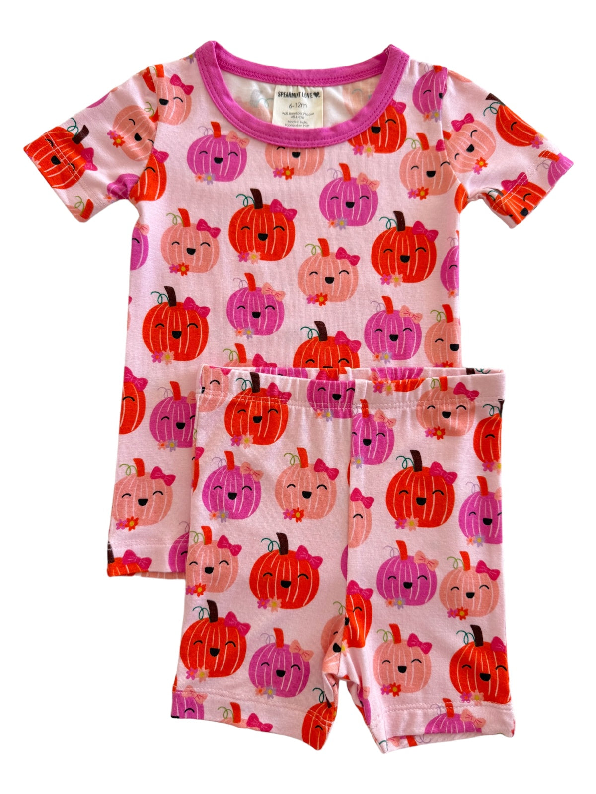 Pink kids’ pajama set featuring colorful, smiling pumpkins in varying shades and wearing bows.