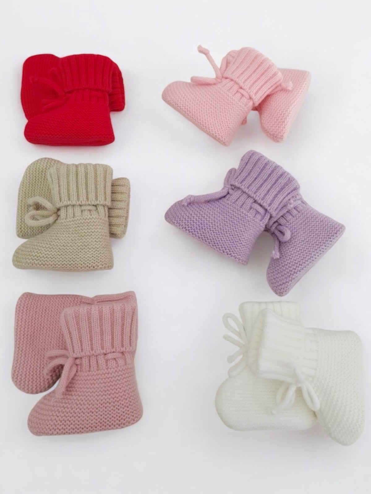Colorful knitted baby booties in red, pink, purple, beige, and white arranged on a light background.