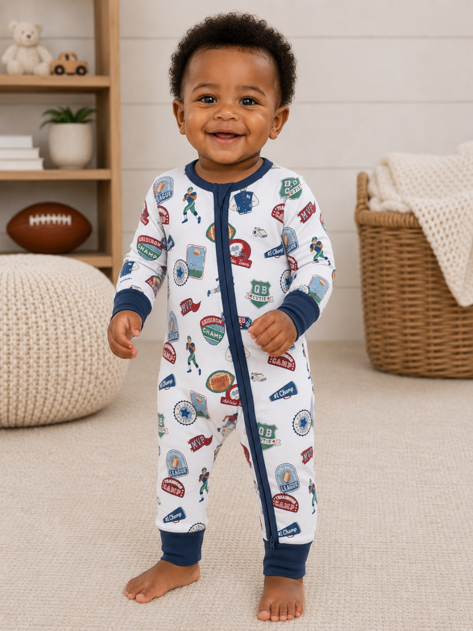 Smiling toddler in football-themed pajamas, standing on a carpeted floor, with toys and decor in the background.