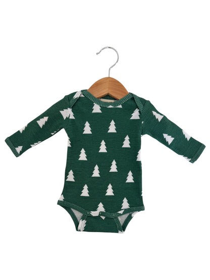 Green baby onesie with white tree patterns, displayed on a wooden hanger against a white background.