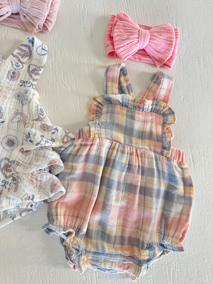 Infant plaid romper with pink, blue, and yellow hues, alongside a pink bow headband and floral top.
