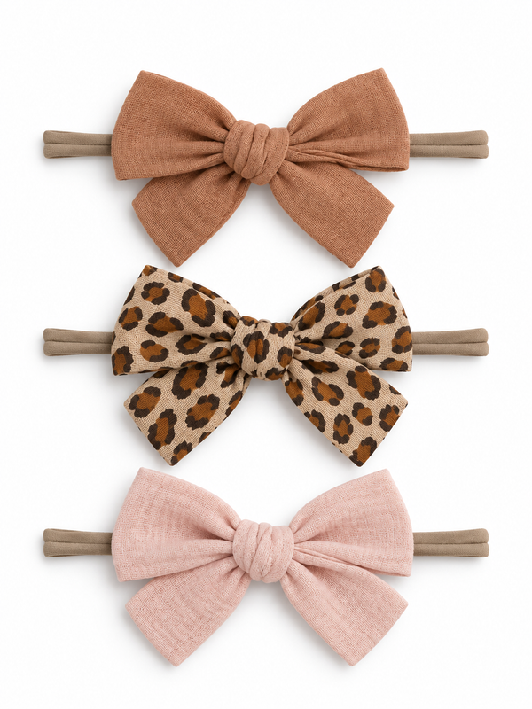 Three hair bows in rust, leopard print, and blush pink on elastic bands, displayed against a white background.