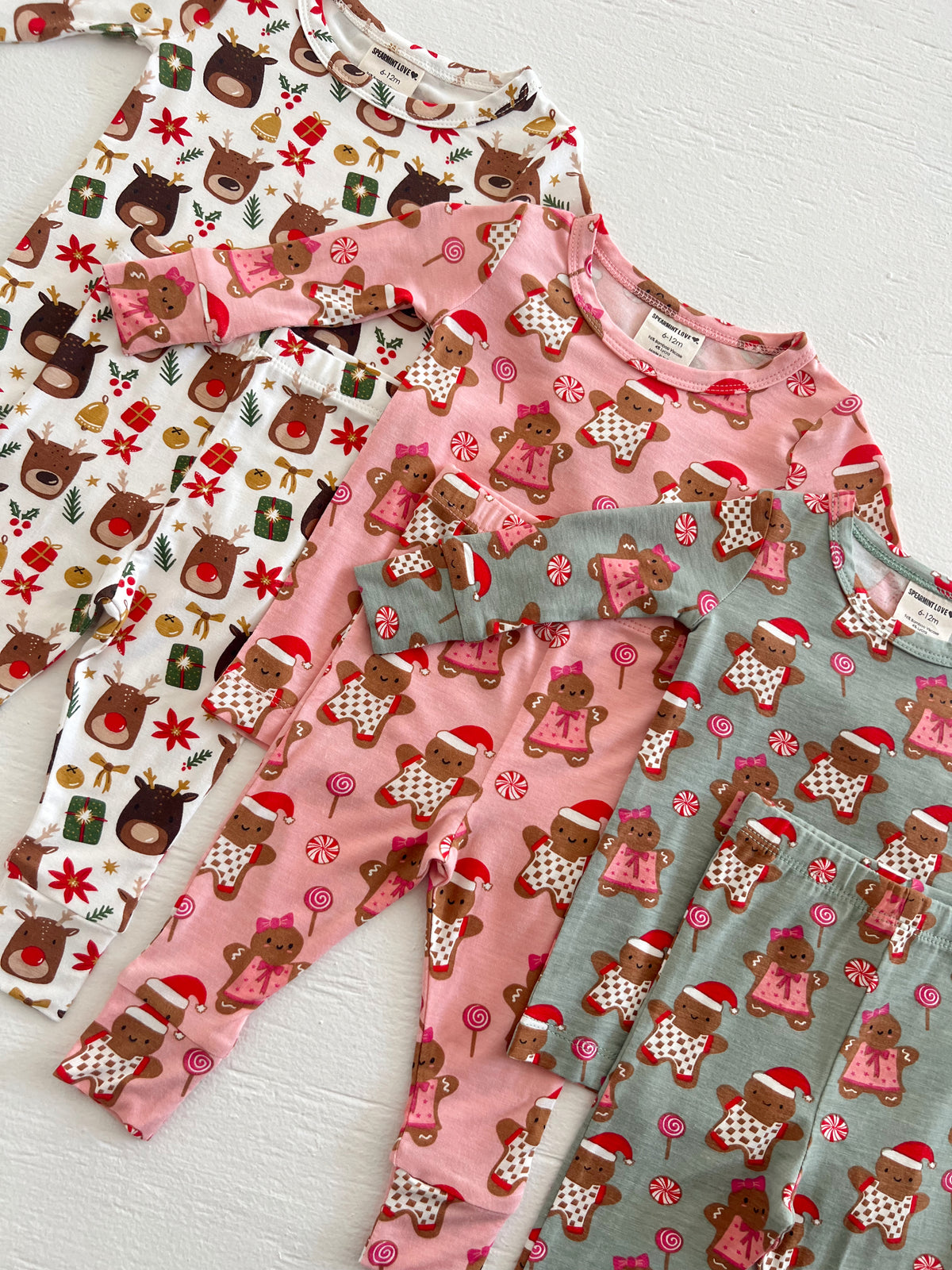 Four pairs of festive children's pajamas featuring reindeer and gingerbread designs in playful colors.