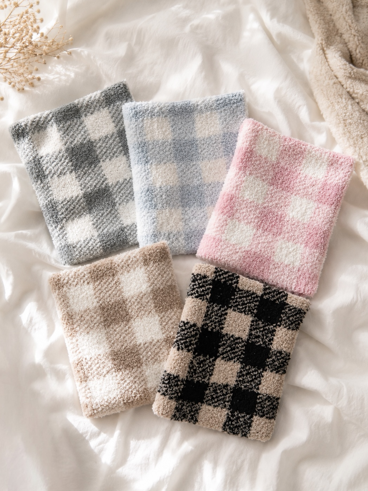 Five colorful, checkered washcloths arranged on a soft, light-colored surface.