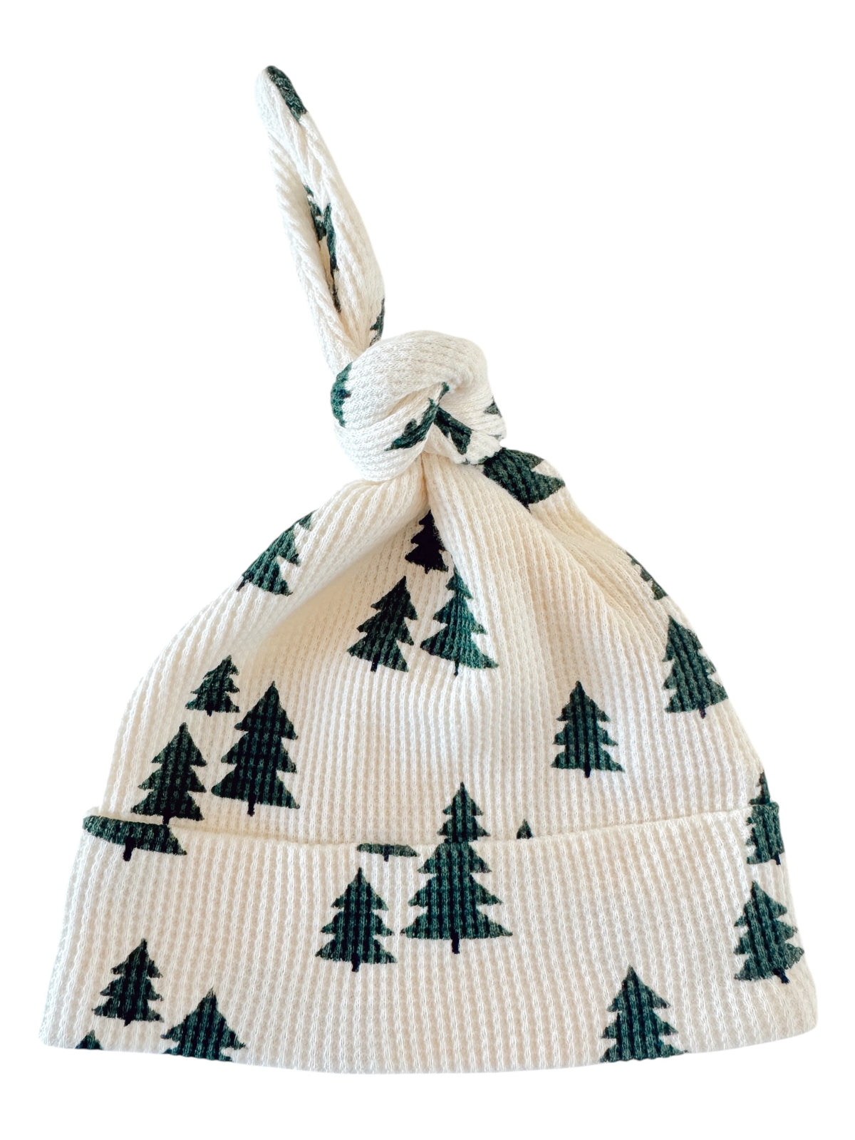 Knotted baby hat with green tree patterns on a white background, ideal for winter outings.