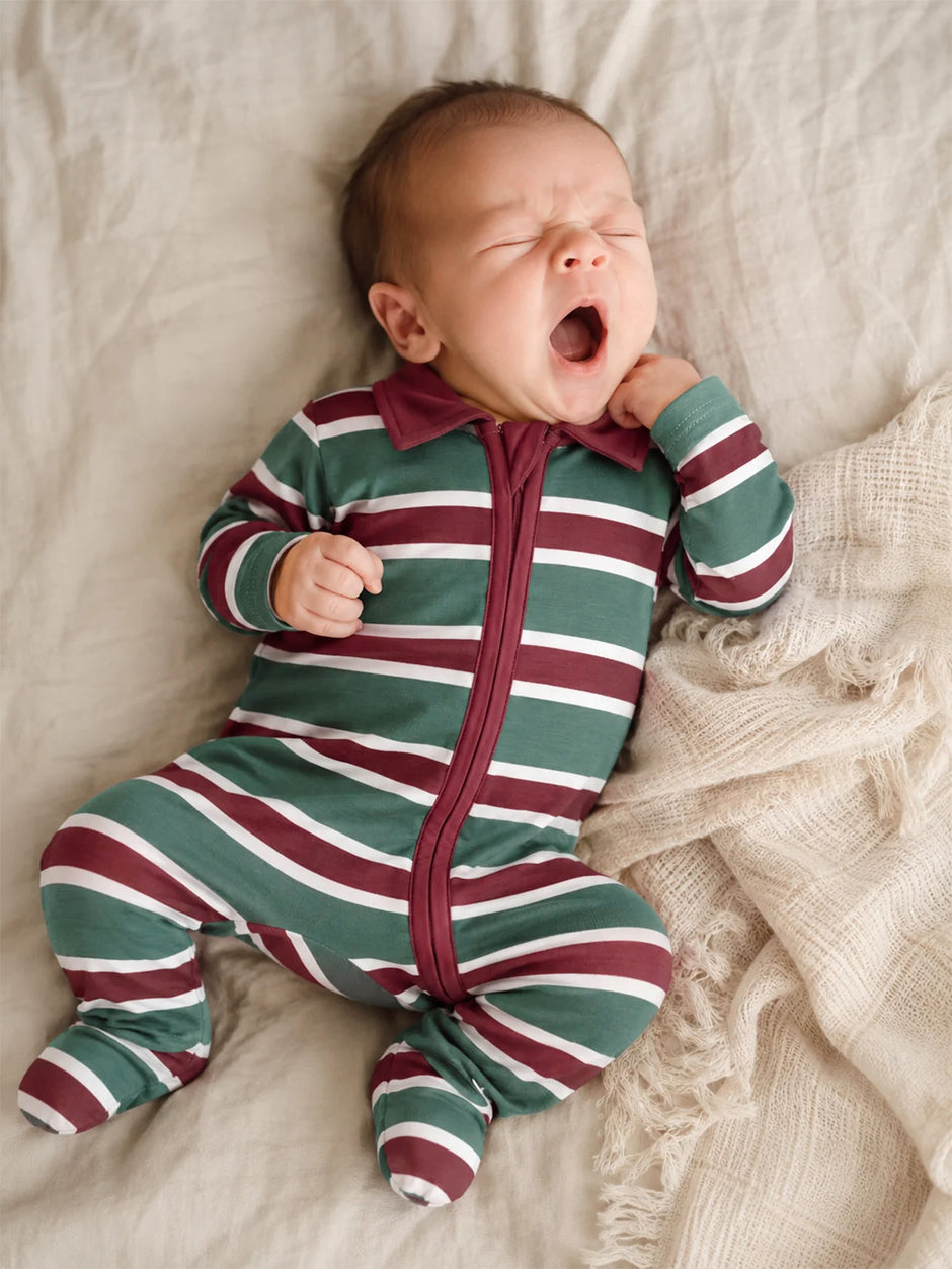 Baby in striped pajamas yawning on a cozy blanket.