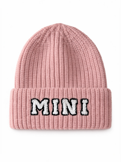 Pink knitted beanie with a folded cuff and the word "MINI" in fluffy white letters.