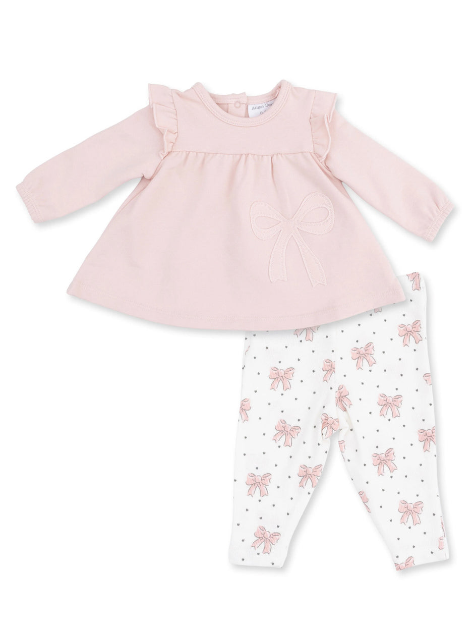 Pink long-sleeve shirt with ruffles and bow, paired with white leggings featuring pink bows and black polka dots.