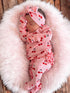 Baby girl peacefully sleeping in pink cherry-patterned outfit on fluffy blanket. Soft textures create a cozy atmosphere.