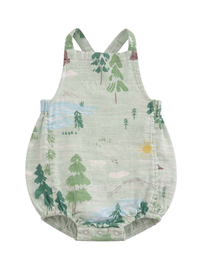 Green baby romper with nature-themed print featuring trees, mountains, and a sun. Adjustable shoulder straps included.