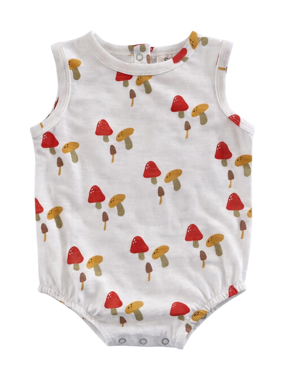 White baby romper with colorful mushroom print in red, yellow, and brown tones.