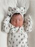 Baby girl sleeping on a textured blanket, wearing a cactus-patterned outfit and a matching bow headband.