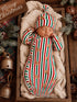 Sleeping baby in festive striped pajamas with gingerbread designs, nestled in a cozy blanket in a wooden crate.