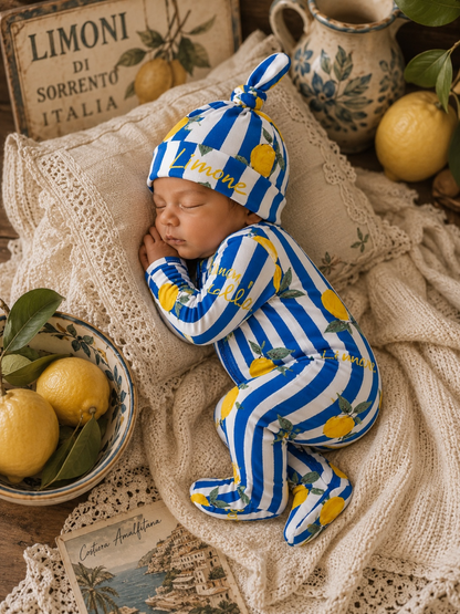 Sleeping baby in blue and white striped outfit with lemons, surrounded by cozy blankets and decorative items.