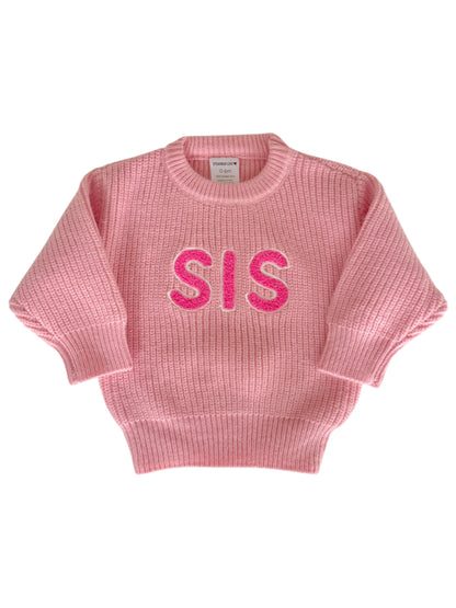 Pink knitted sweater with "SIS" in bright pink letters on the front, designed for infants and toddlers.