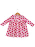 Pink long-sleeve dress with cupcake pattern on a wooden hanger.