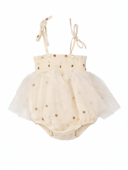 Cream-colored baby dress with polka dots and tulle skirt, featuring adjustable straps for a snug fit.