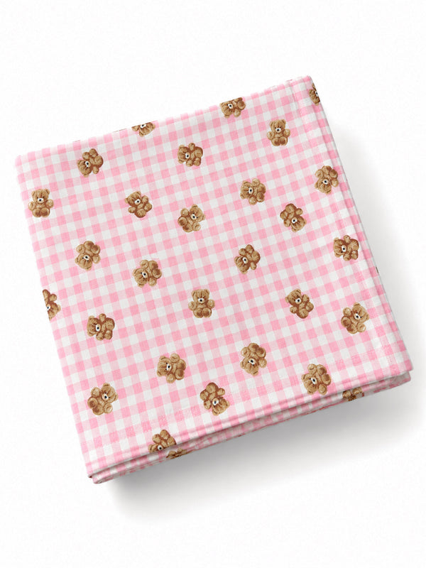 Pink gingham cloth with small teddy bear illustrations scattered across the fabric.