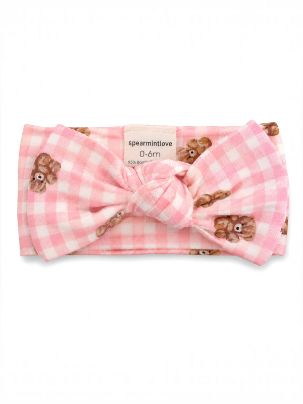 Pink baby headband with teddy bear prints and a large knot, suitable for infants 0 to 6 months.