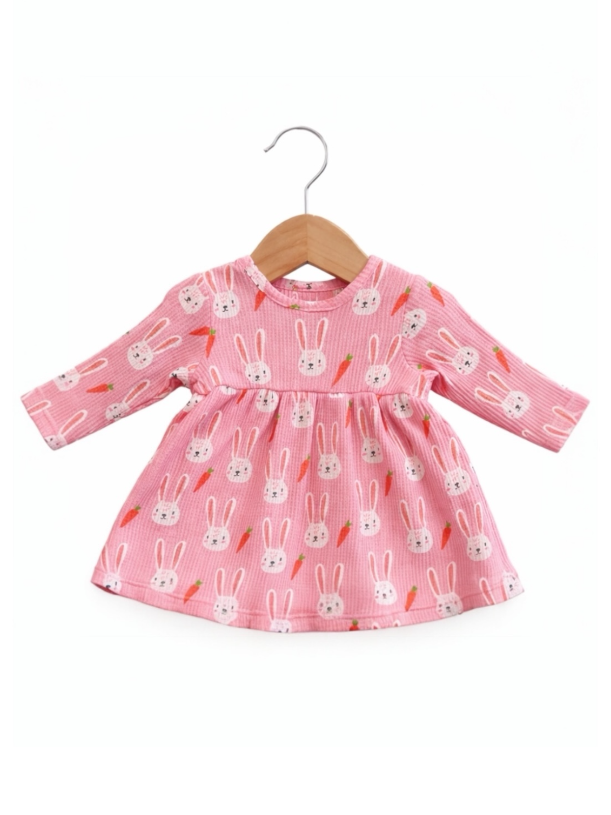 Pink dress with bunny and carrot pattern, hanging on a wooden hanger. Perfect for kids' spring fashion.
