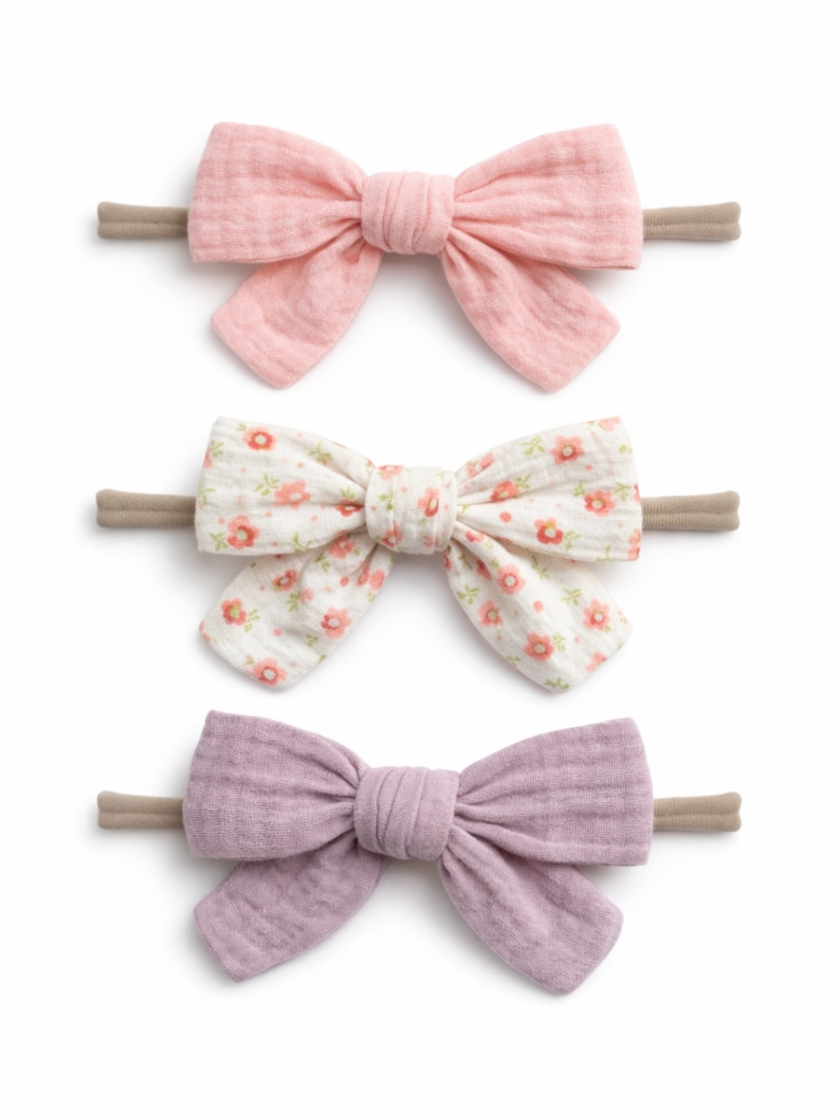 Three hair bows in pink, floral, and lavender fabric, each attached to a hair elastic.