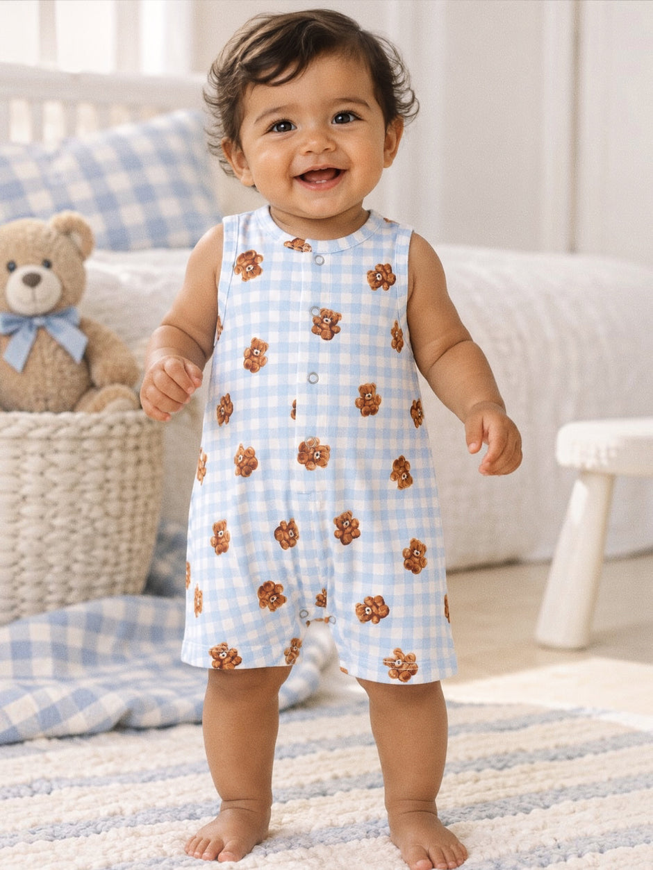 Smiling toddler in a bear-printed onesie, standing on a soft rug with a toy bear in the background.