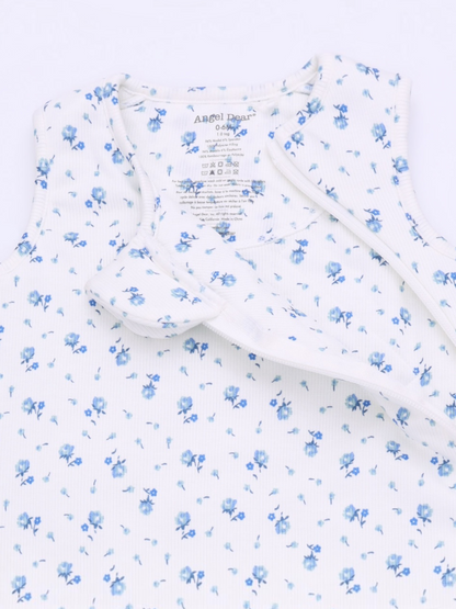 Floral-patterned baby outfit with soft fabric and tag details, featuring blue flowers on a white background.