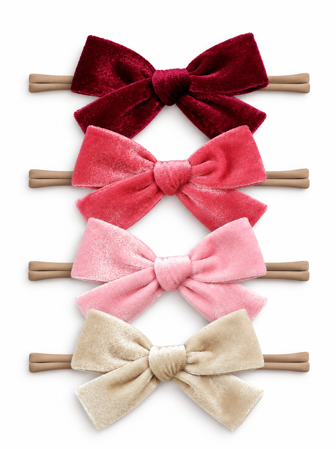 Four different velvet hair bows in shades of red and pink on elastic bands.
