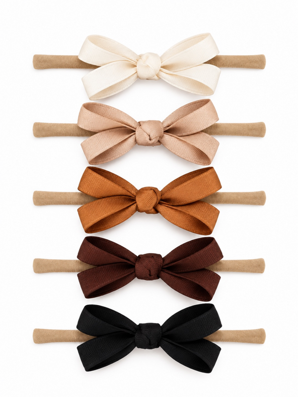 Five fabric hair bows in ivory, tan, rust, dark brown, and black arranged on a white background.