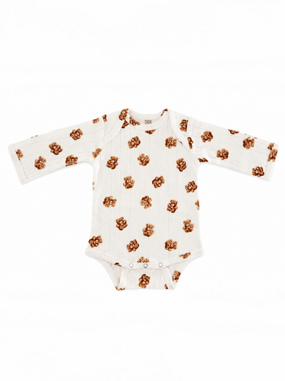 White baby onesie with long sleeves and a floral pattern in brown tones.