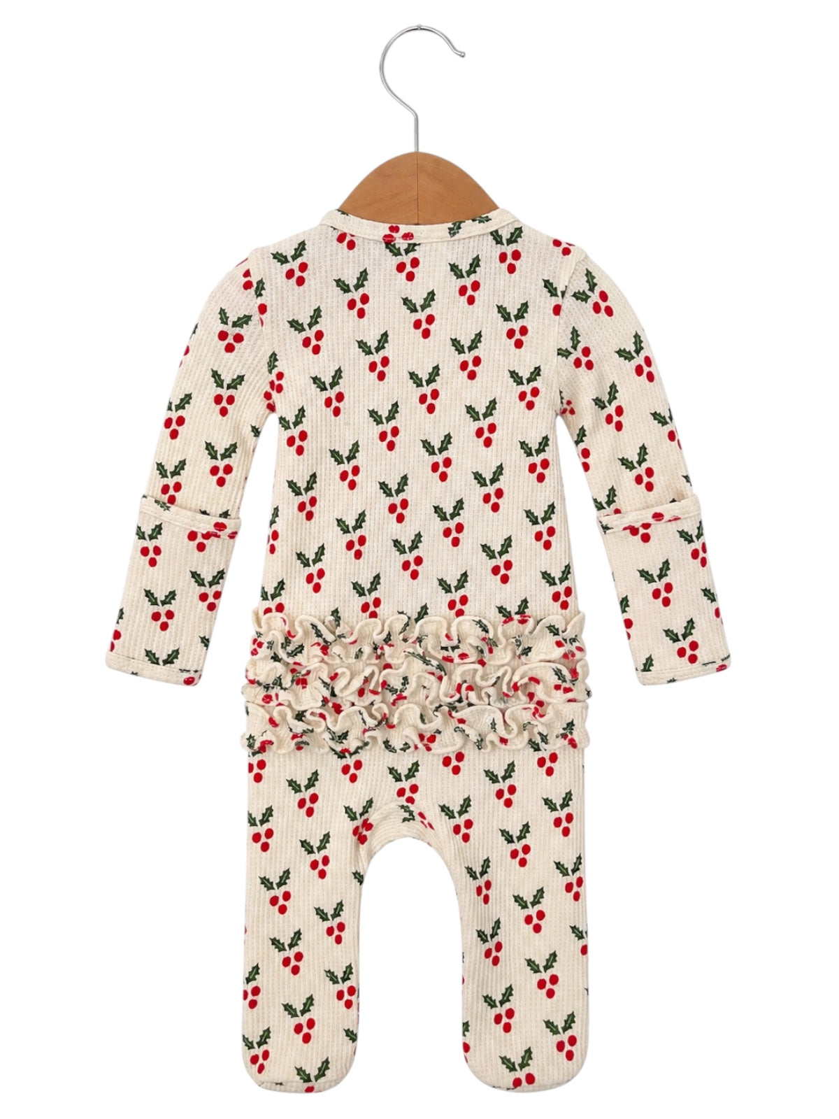 White romper with red berry and green leaf print, featuring a ruffled waist, hanging on a wooden hanger.