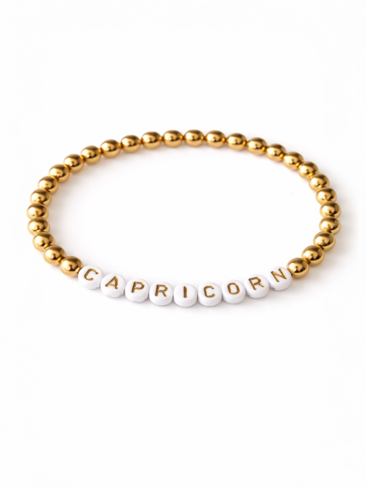 Gold and white beaded bracelet with the word "CAPRICORN" spelled in letter beads.