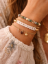 Close-up of a wrist adorned with bracelets, featuring the word "CAPRICORN" and various gemstones on delicate chains.