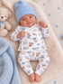Smiling baby in a blue hat and sports-themed outfit, surrounded by plush toys and soft blankets.